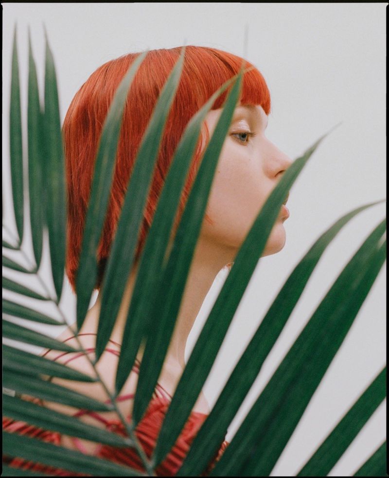 Woman poses behind plant for Pap Magazine