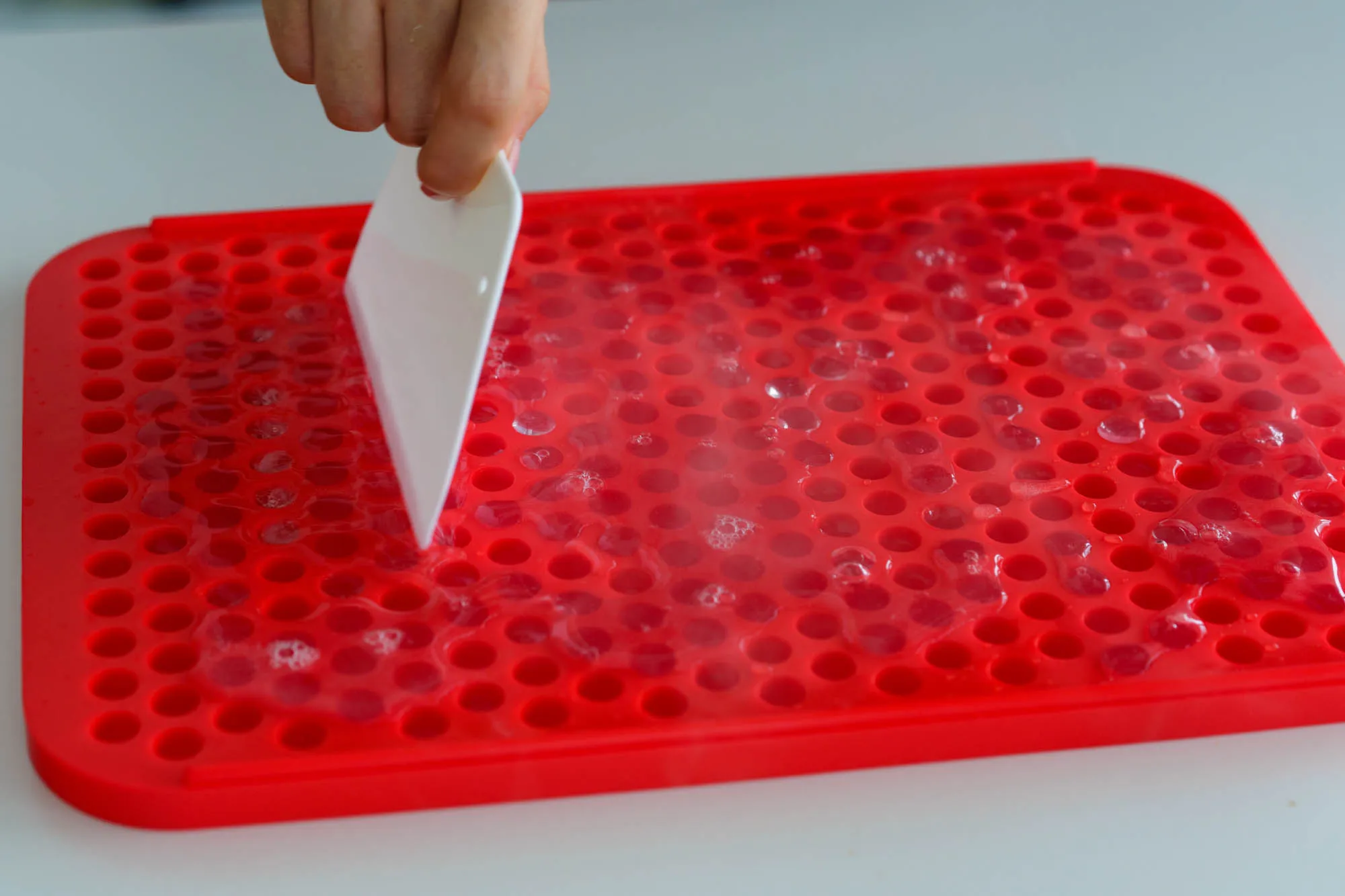 key tip, use a spatula to spread the liquid to fill each of the small holes in the mold. 